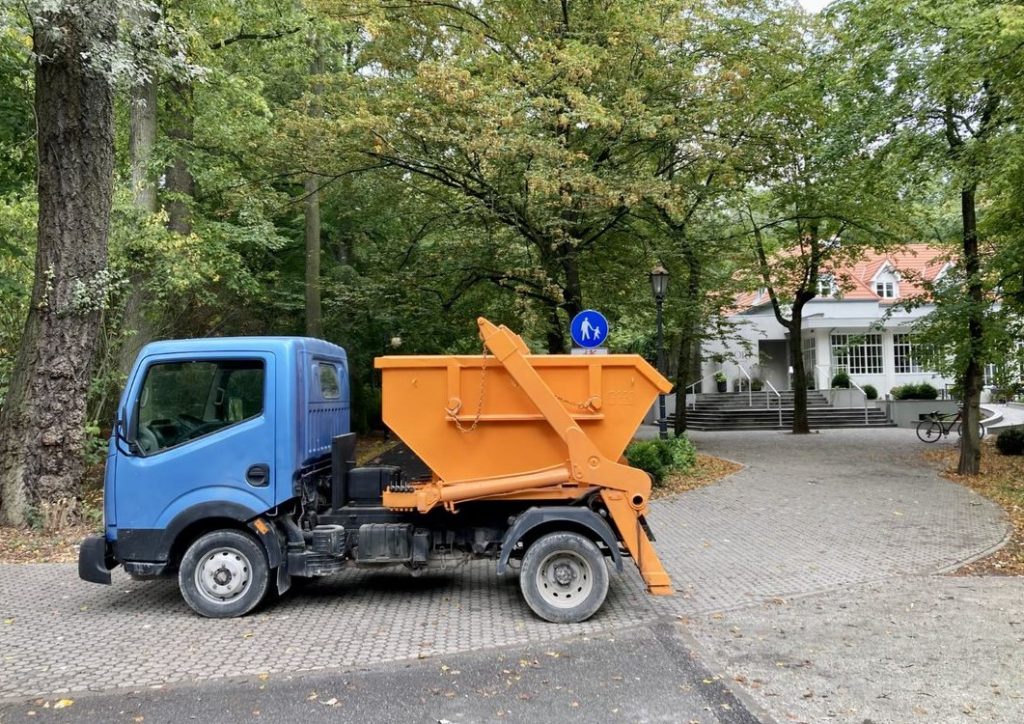 samochód z pomarańczowym kontenerem na gruz