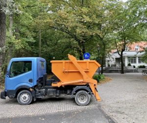 samochód z pomarańczowym kontenerem na gruz